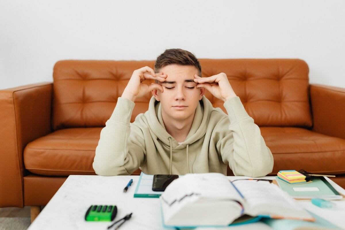 Studente con libro aperto che fatica a concentrarsi mentre studia procrastinazione