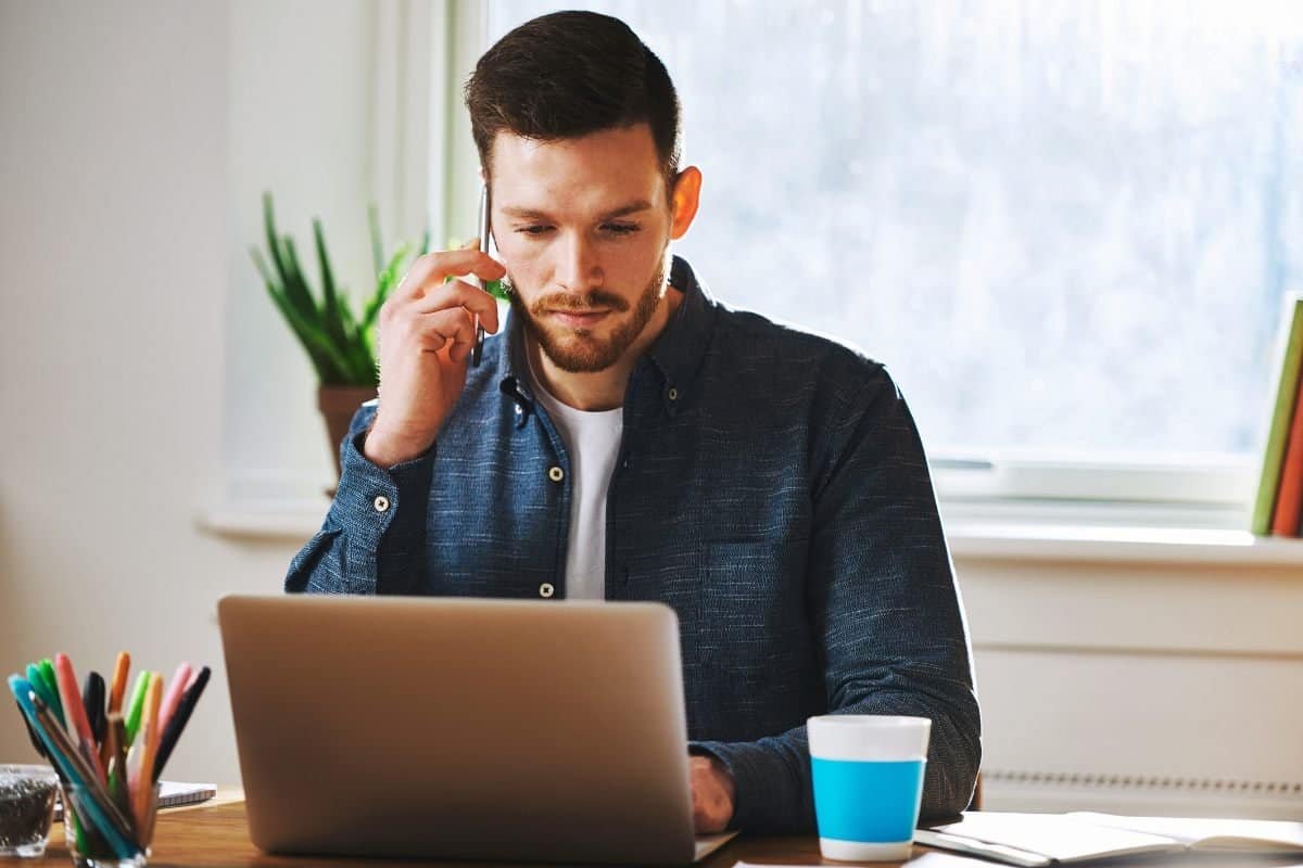 uomo che lavora al laptop mentre riceve una telefonata distrazioni durante il lavoro