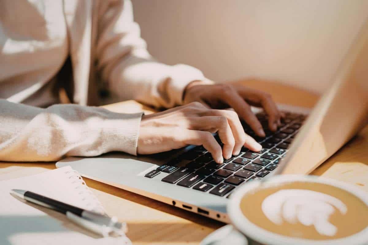 persona che scrive al computer con caffè simbolo di routine e micro abitudini