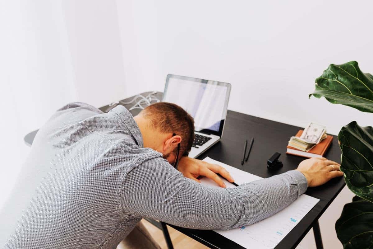 uomo stanco crollato sulla scrivania procrastinazione esaurimento mentale