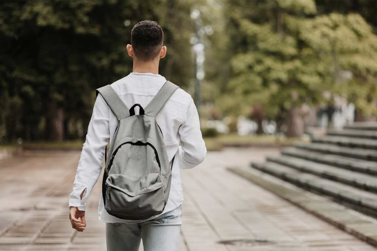 Giovane con zaino che cammina in città, immagine utilizzata per un articolo sul rapporto tra adolescenti, furti e denunce.