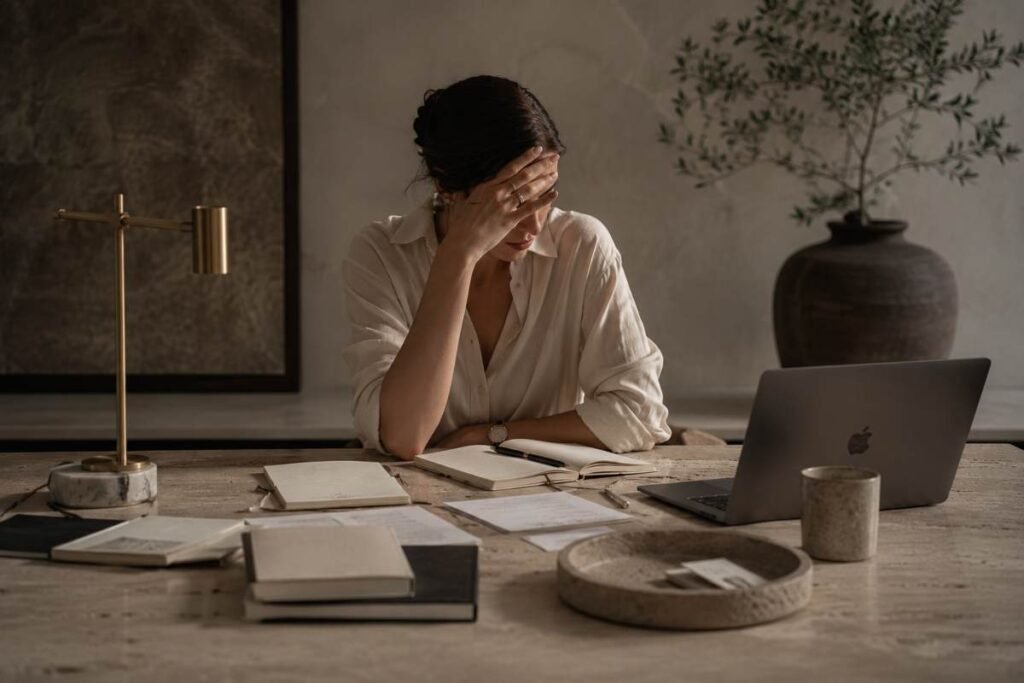 Donna con la mano sulla fronte mentre lavora al computer, simbolo della difficoltà di concentrazione e della perdita di focus.