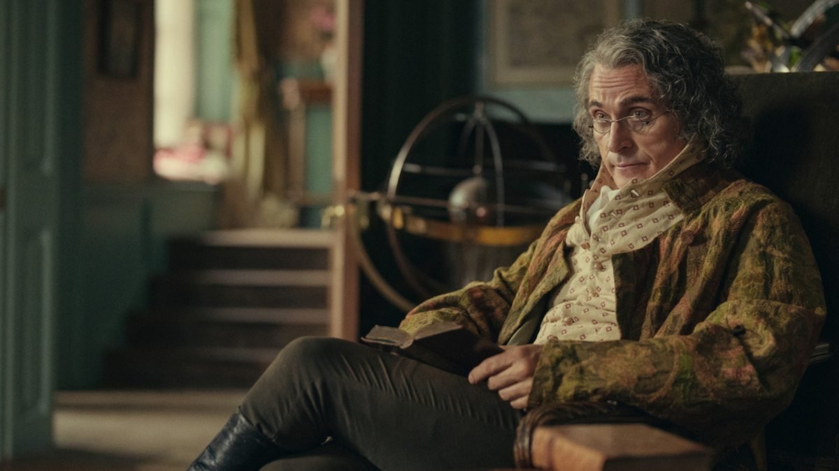 Rufus Sewell con libro e occhiali interpreta Mr Bennet nella serie Netflix Orgoglio e Pregiudizio
